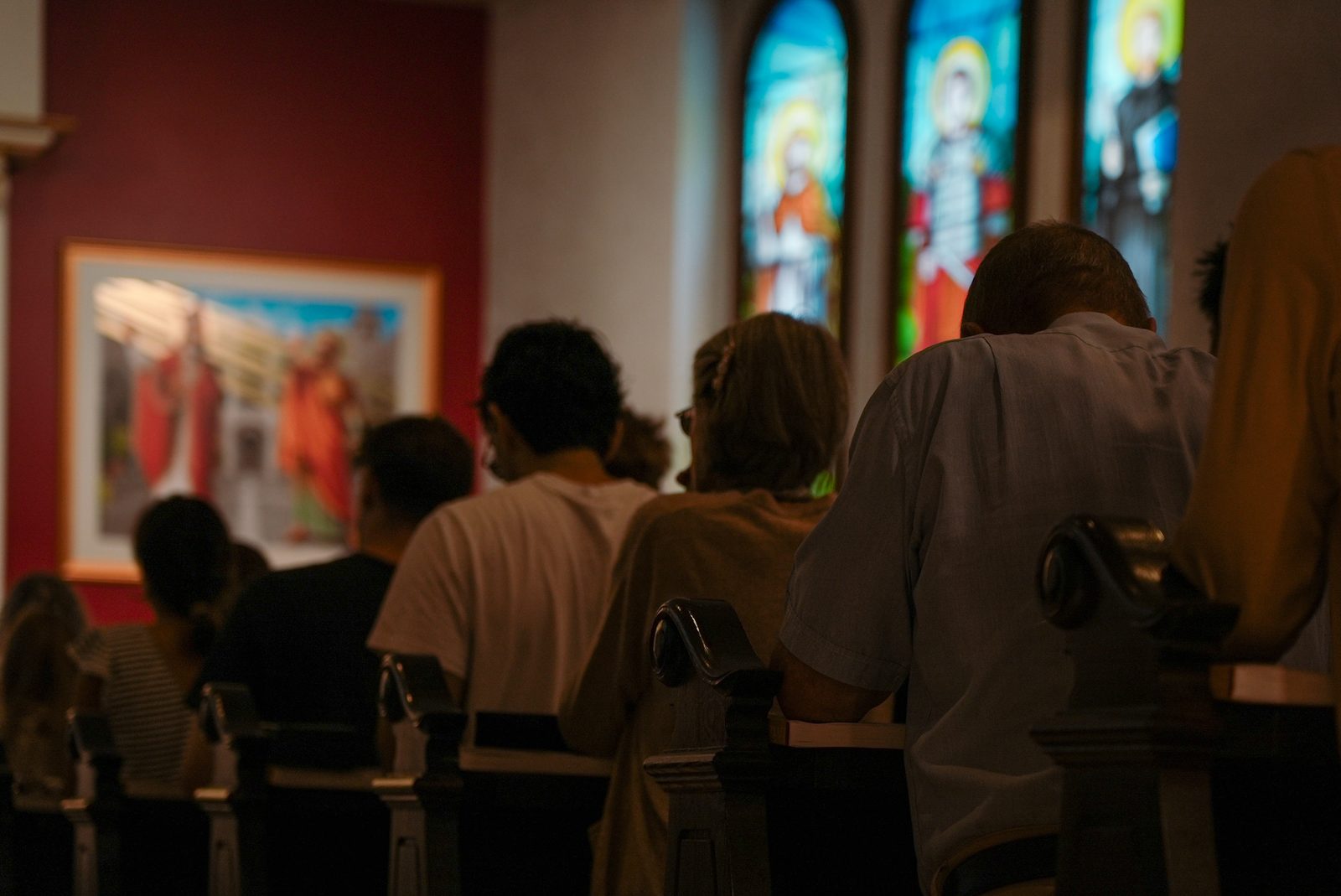 Fidèles en prière devant les vitraux de la chapelle